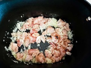 Photo of onion and chicken sauteeing in butter in a slow cooker.