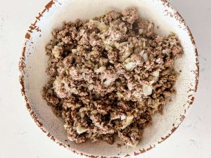 Seasoned cooked ground beef and onion in a rustic white bowl.