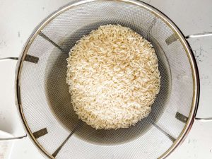 Photo of jasimine rice in a mesh strainer about to be rinsed.