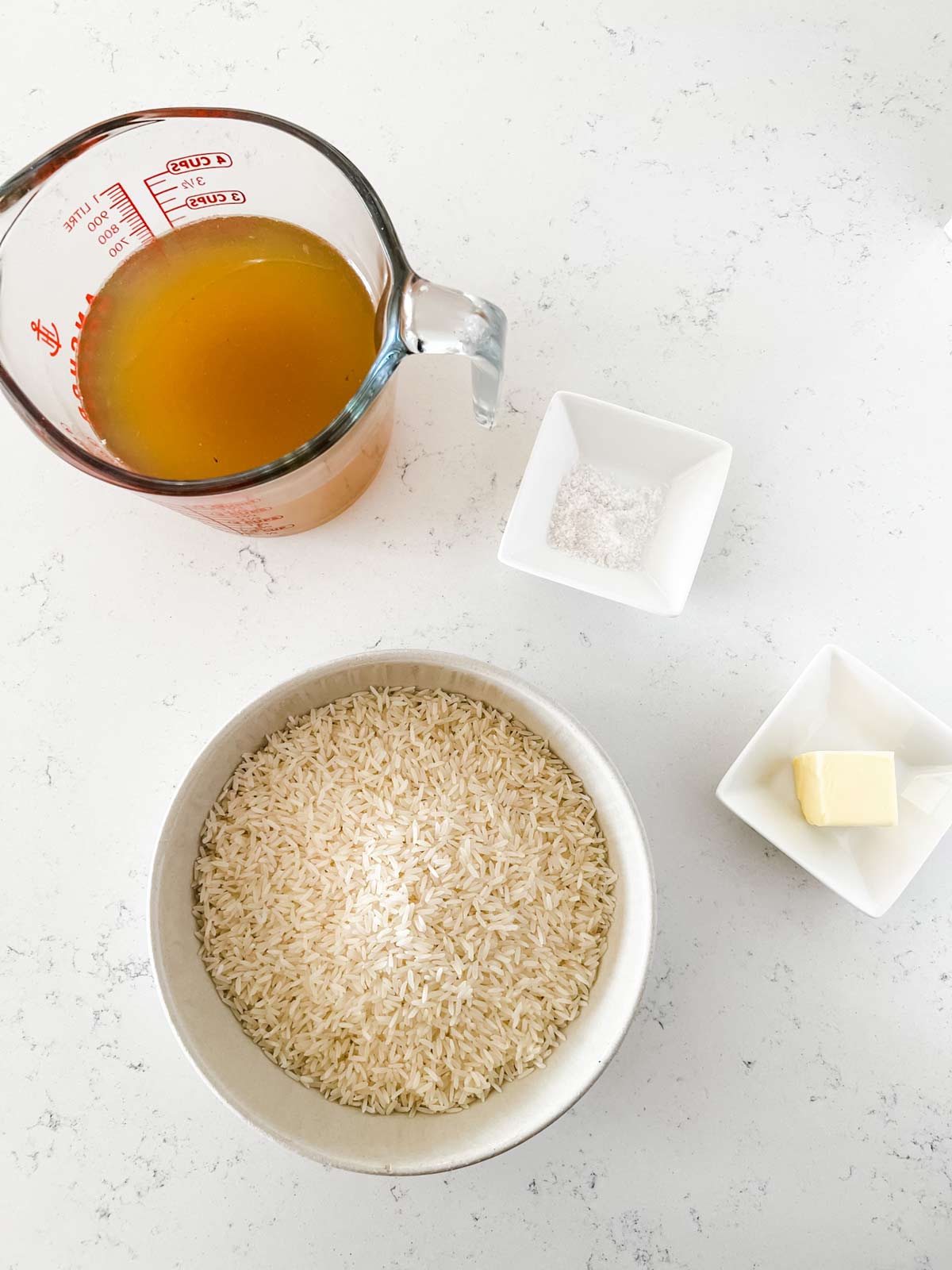 Overhead photo of broth, salt, butter, and rice.