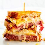 Square photo of an air fryer reuben cut in half and stacked on a white background.