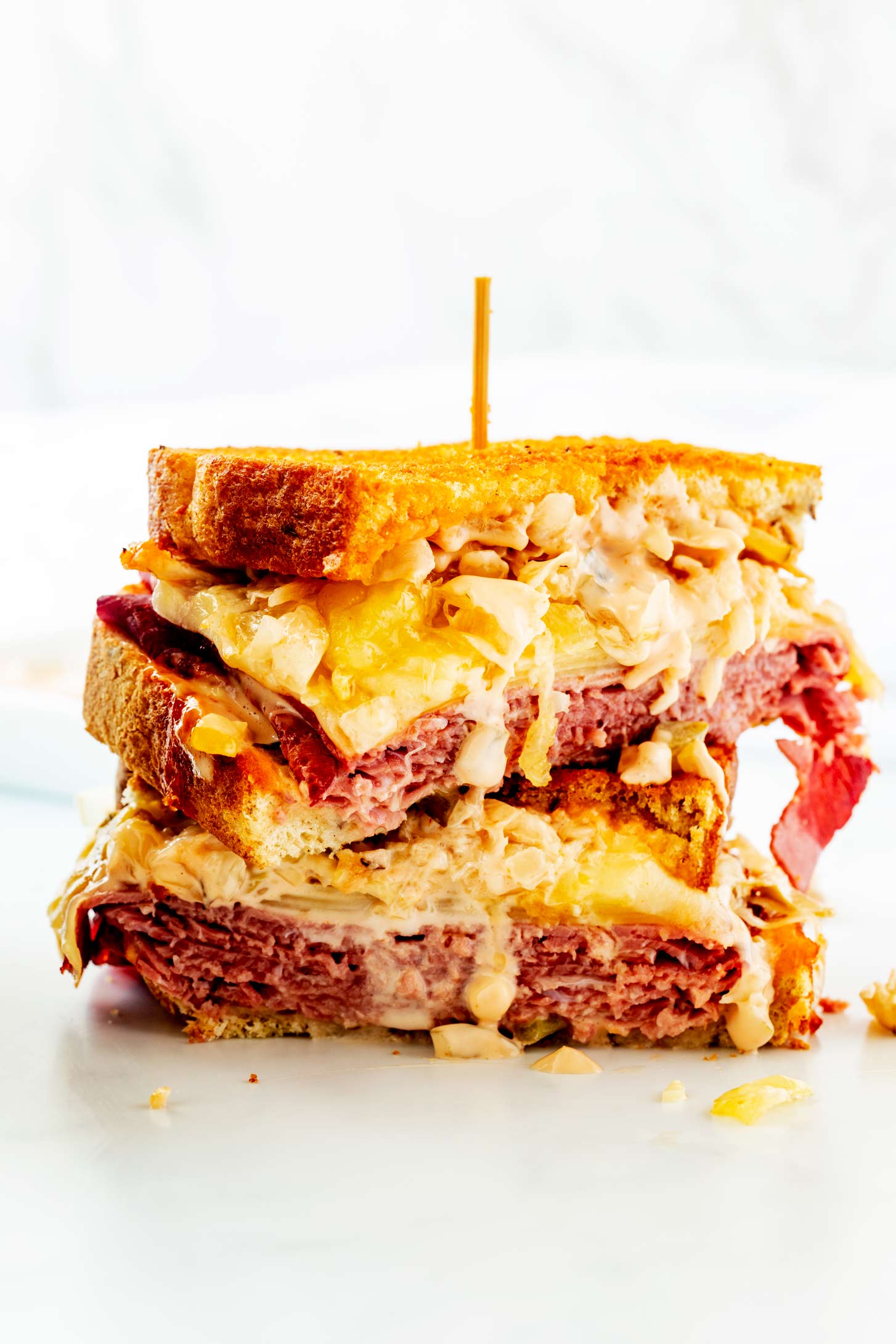 Photo of an air fryer Reuben cut in half and stacked with a skewer through the sandwich.