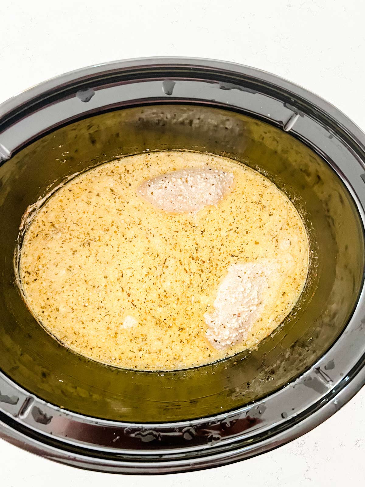 Chicken that has cooked in a creamy sauce in a slow cooker.