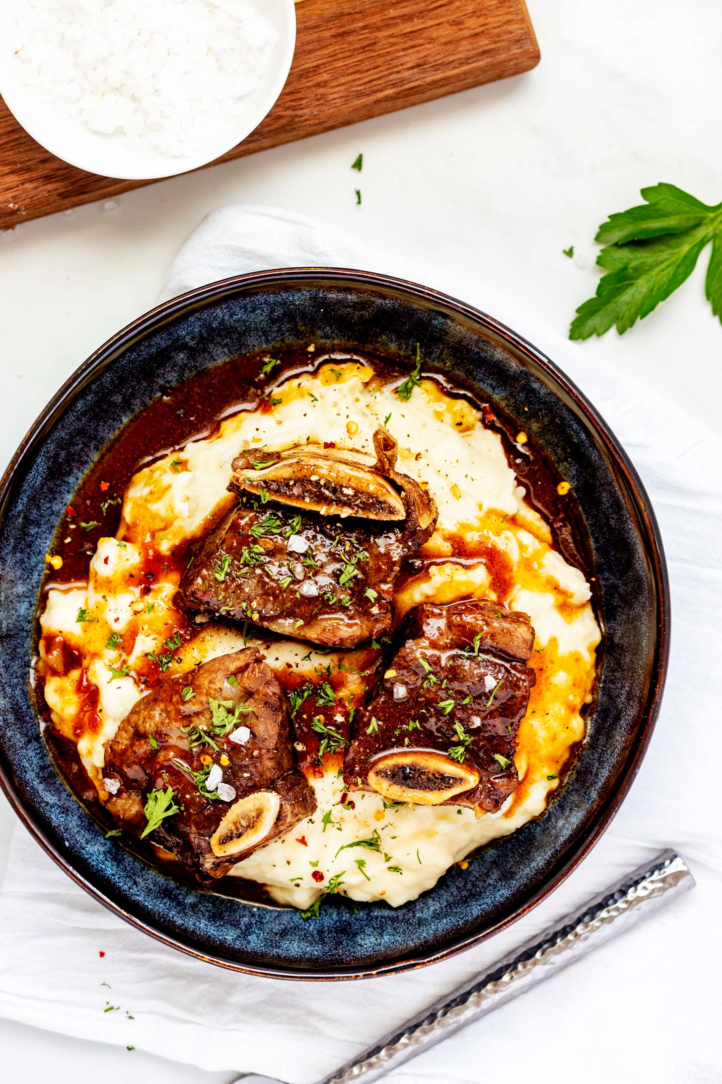 Overhead photo of a shallow blue bowl with Instant Pot beef ribs on a bed of mashed potatoes.