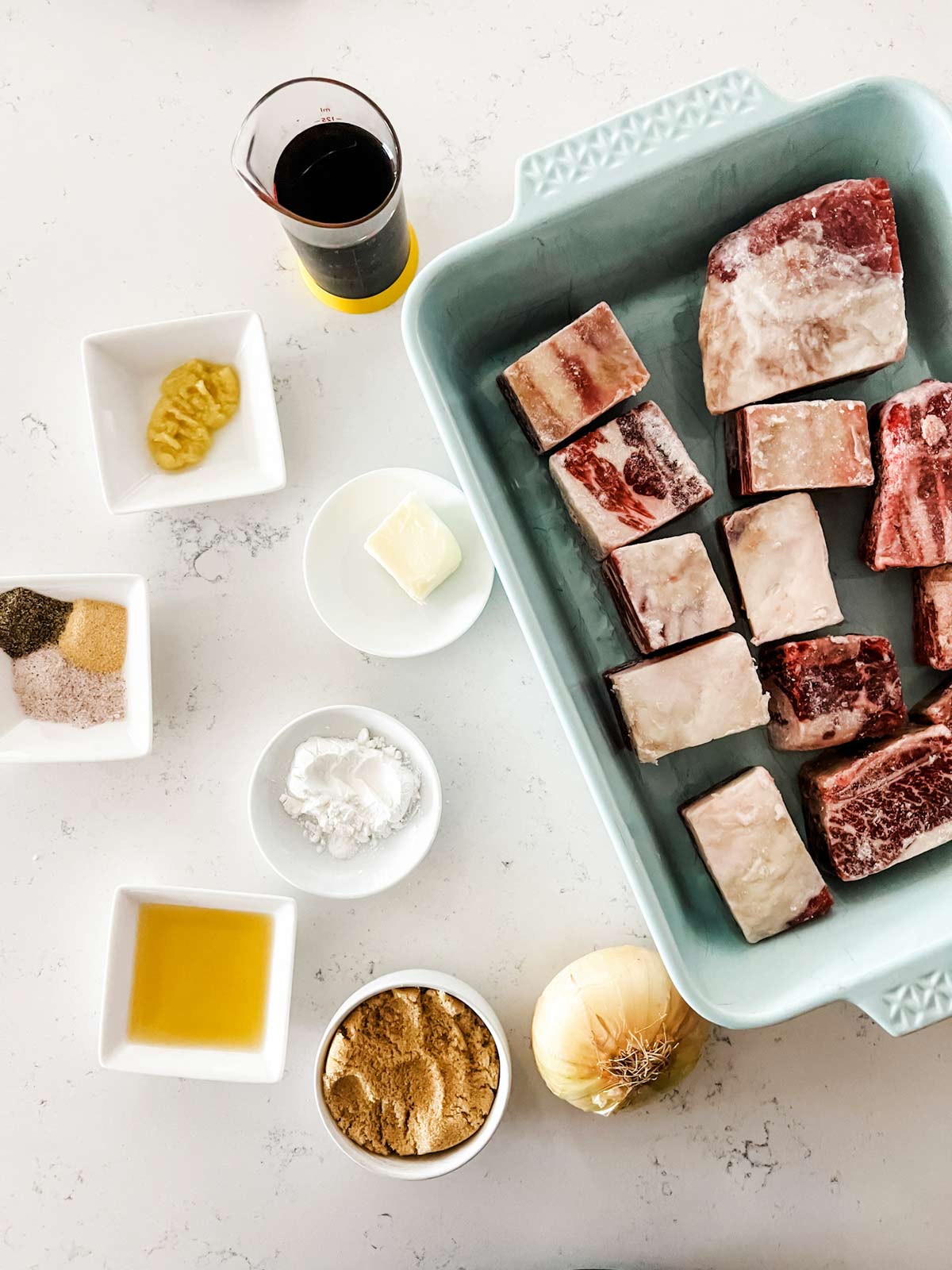 Soy sauce, water, light brown sugar, sesame oil, sea salt, garlic powder, fresh grated ginger, black pepper, bone-in short ribs, butter, yellow onion finely chopped and cornstarch in prep containers.