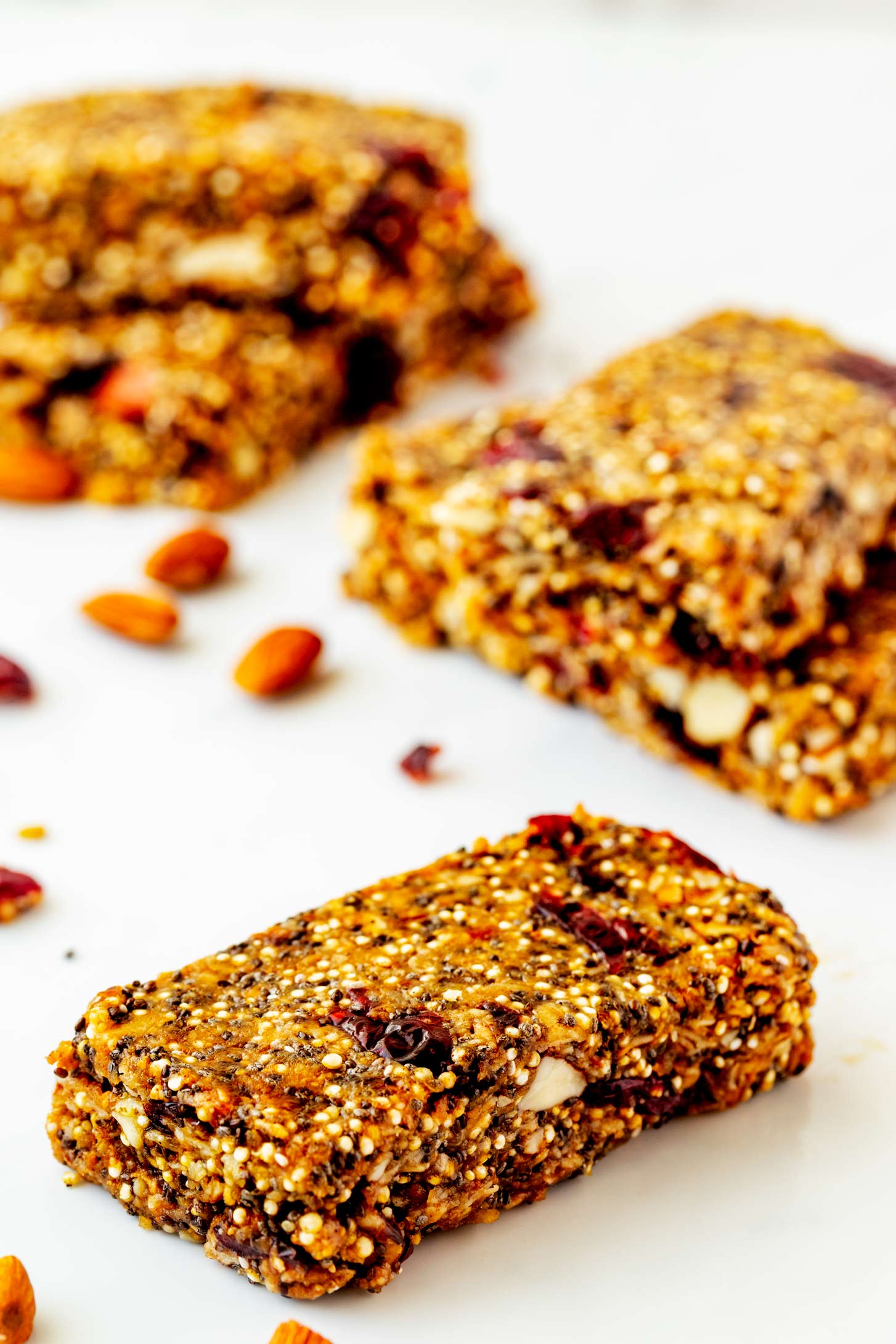 Photo of a protein power bar sitting in front of two stacks of protein power bars with almonds and cranberries beside it.