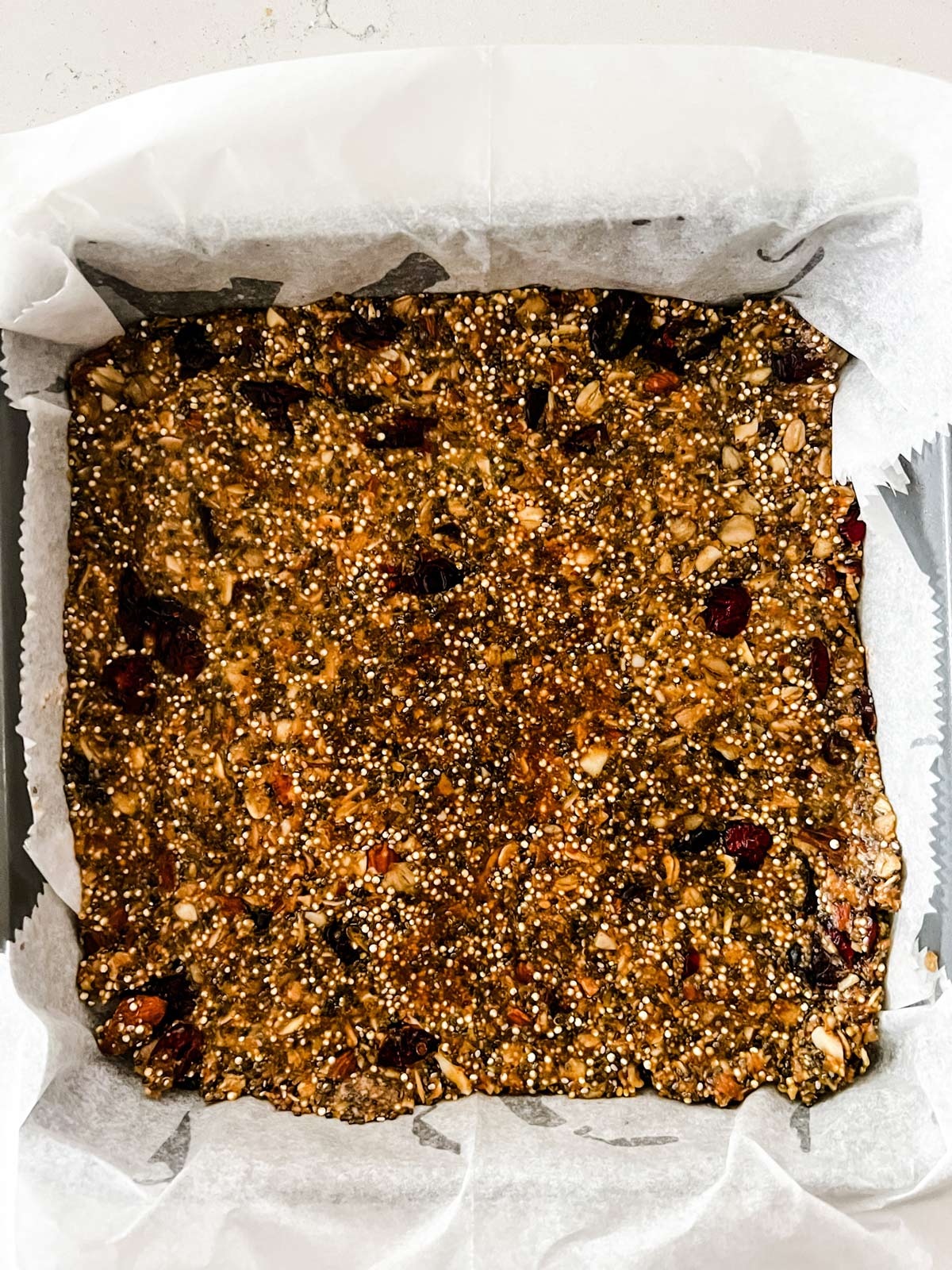A parchment lined square pan with protein power bars in it.