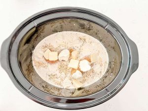 Chicken, broth, cream, buter, cream cheese, and seasonings in a slow cooker.