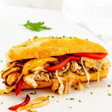 Photo of a chicken philly garnished with parsley on a white countertop.