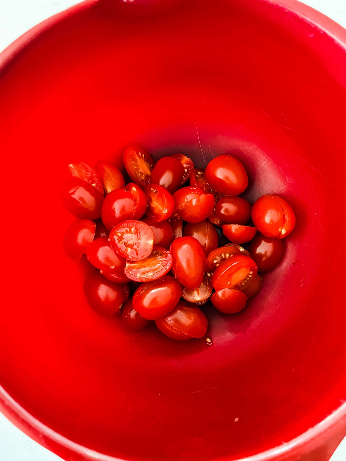 Halved grape tomatoes in a large bowl.