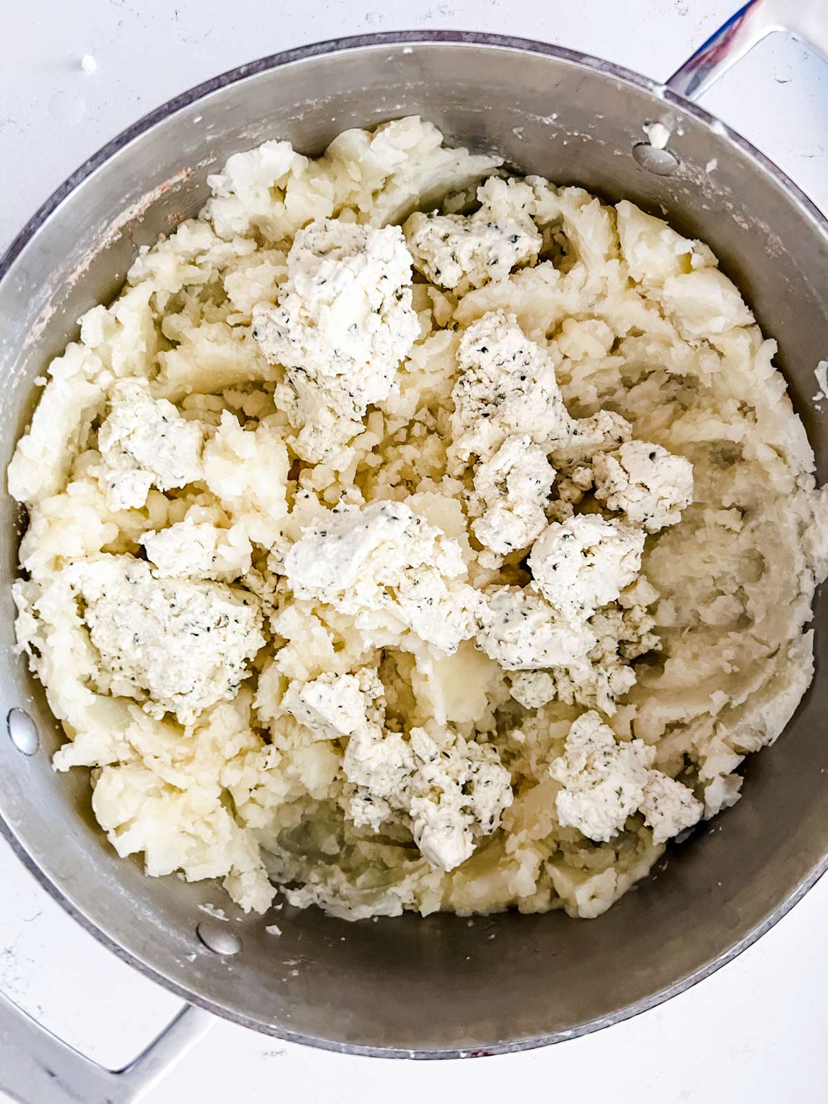 Mashed potatoes with boursin cheese and seasonings on top.