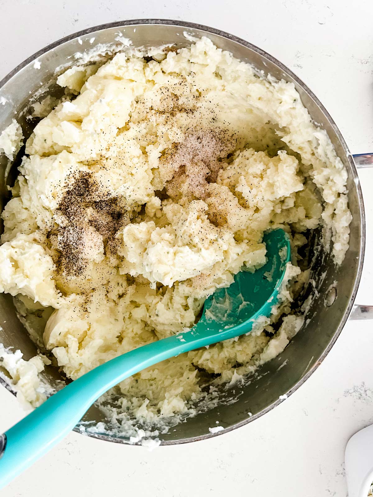 A spoon stiring together a bowl of Boursin mashed potatoes.