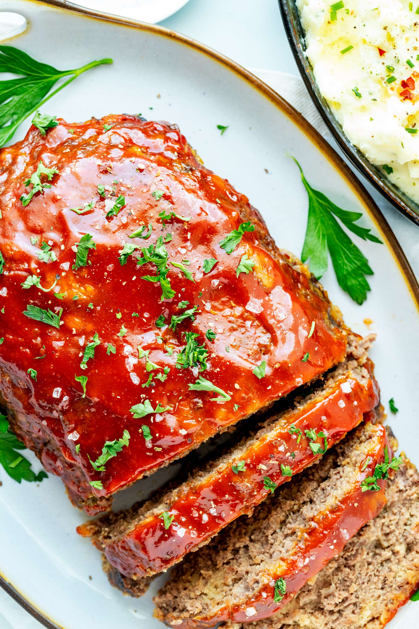 Overhead photo of a partially sliced slow cooker meatloaf on a serving platter.