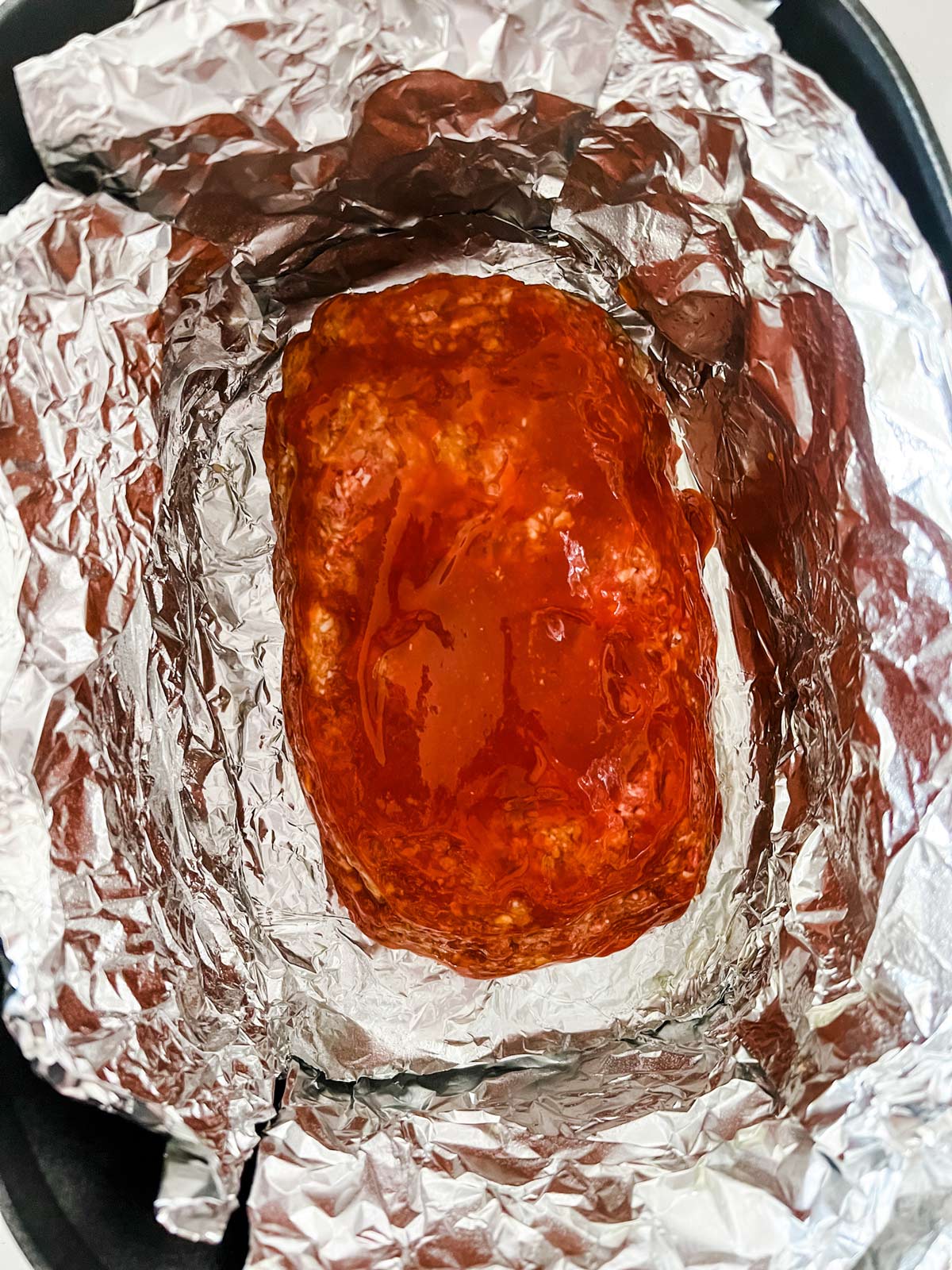 A glazed meatloaf in a slow cooker ready to cook.