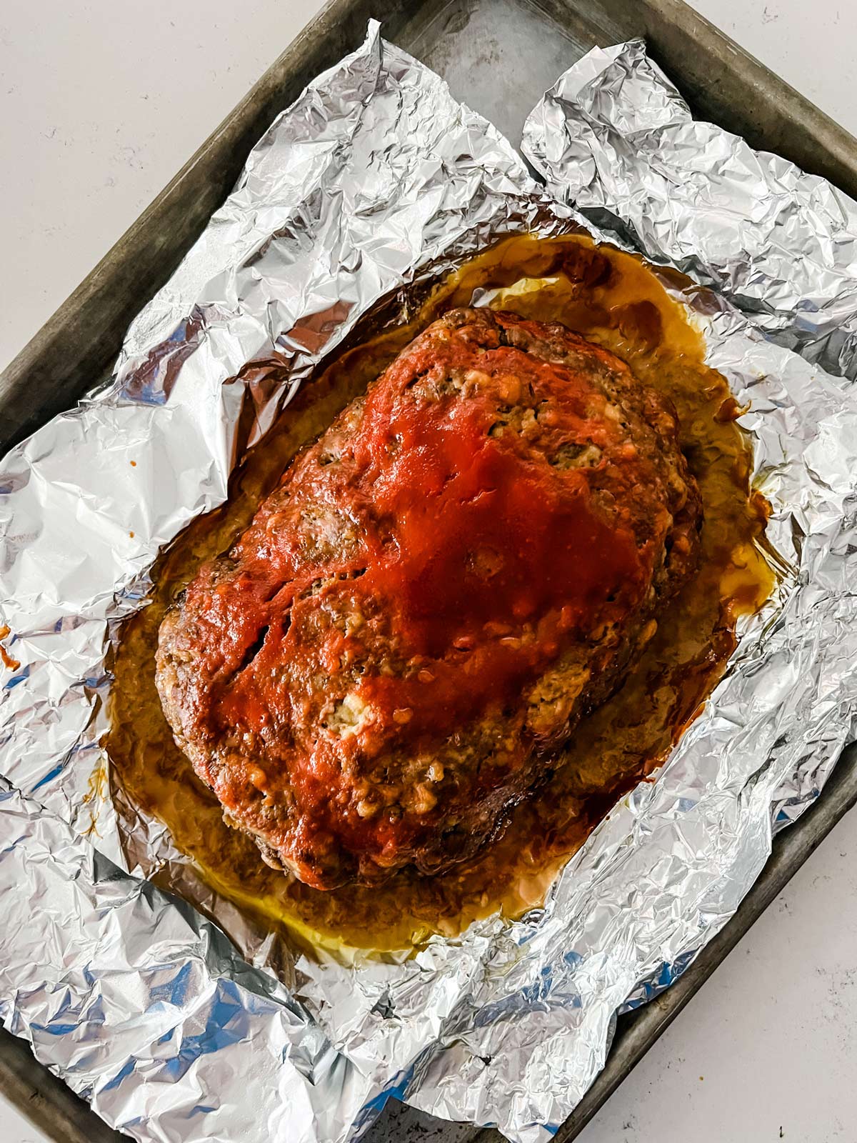 A foil lined baking sheet with a meatloaf on it.