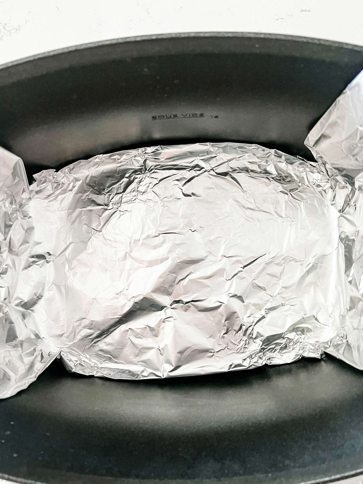 The bottom part of a foil sling in a slow cooker.