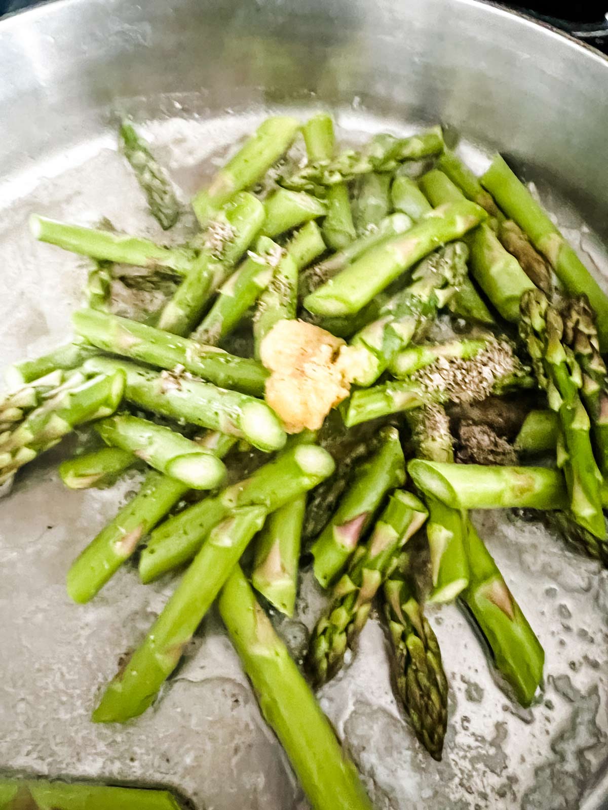 Asparagus, garlic, and butter that have just been added to a skillet.