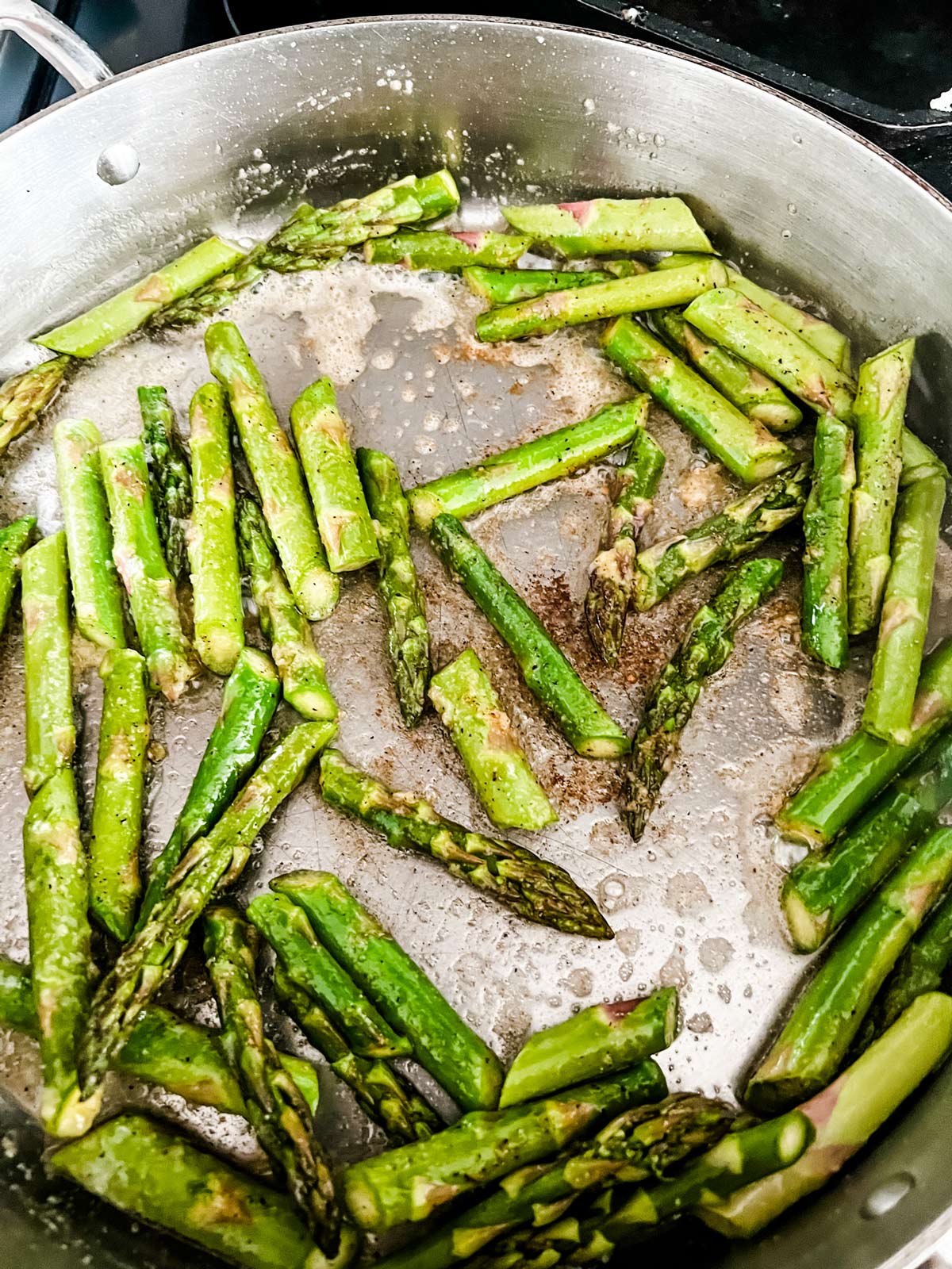 Asparagus that has cooked with garlic and butter in a skillet.