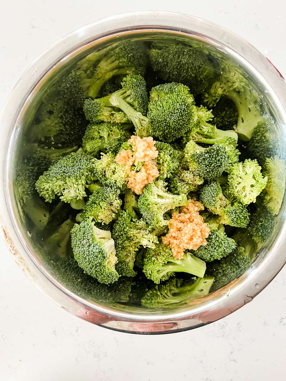 Garlic, broccoli and seasonings in a bowl.