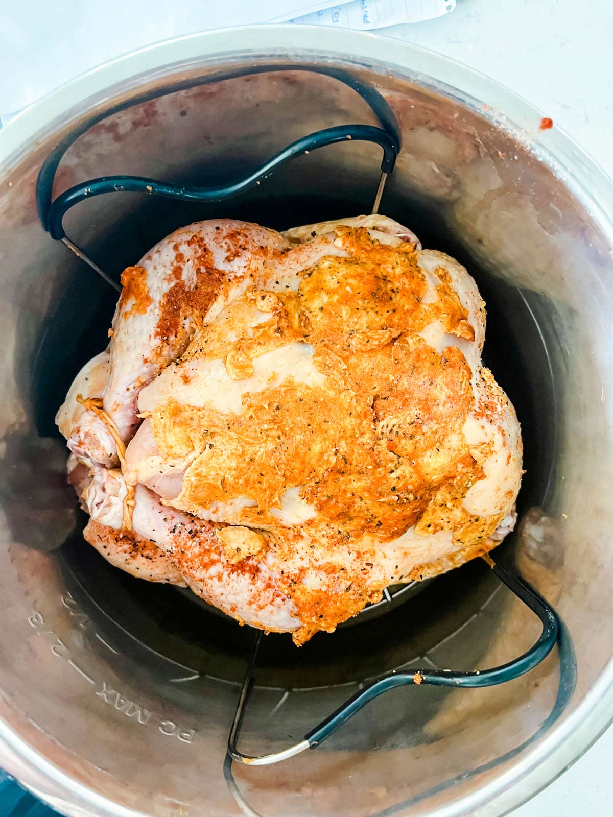 A buttered and seasoned chicken ready to cook in an Instant Pot.