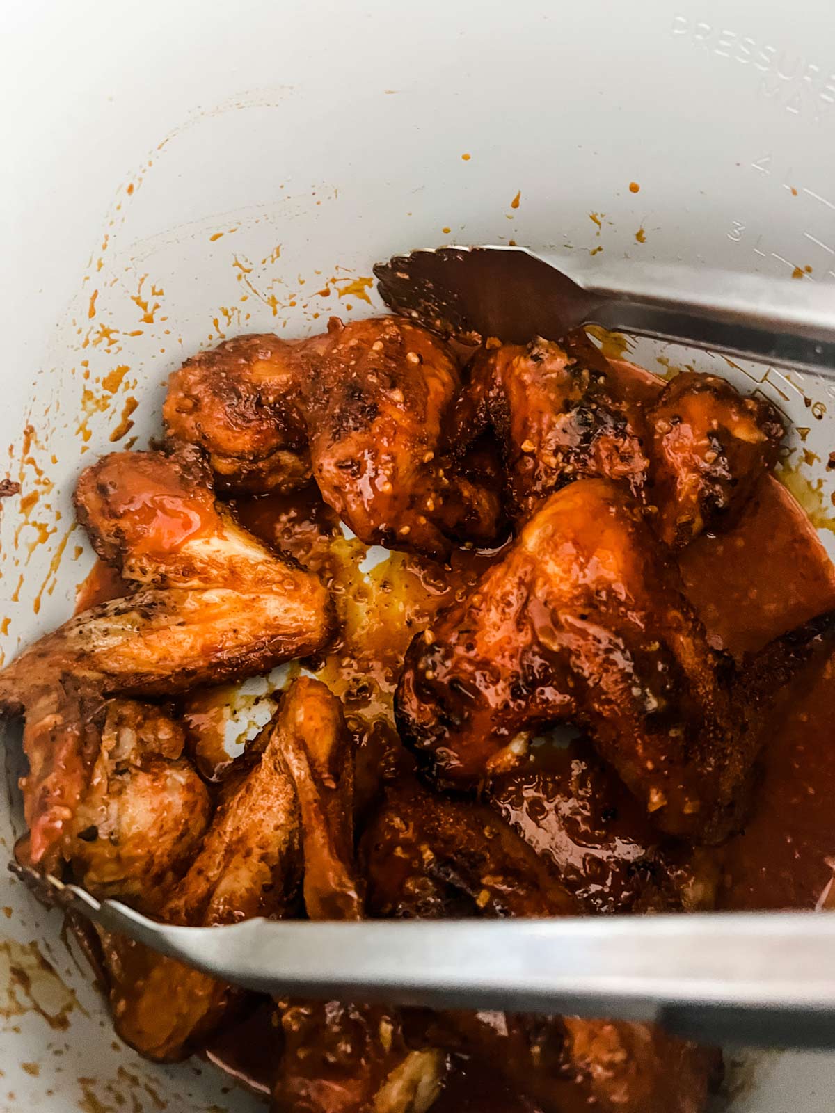 Chicken wings tossed with a homemade buffalo sauce in the pot of a Ninja Foodi.