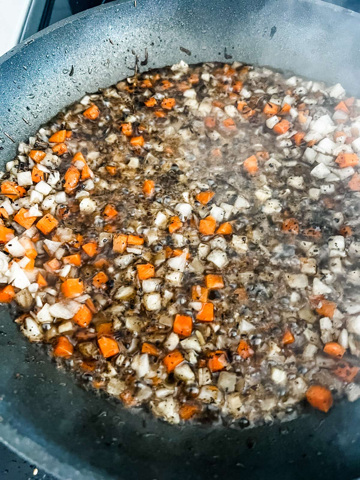Diced vegetables sauteeing in the rendered fat from beef ribs.