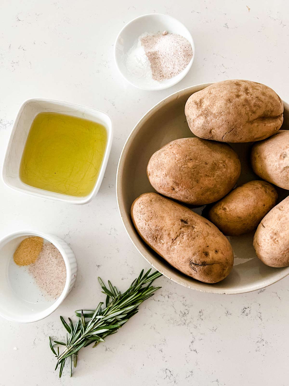 Overhead photo of potatoes, oil, rosemary, baking soda, and seasonings.