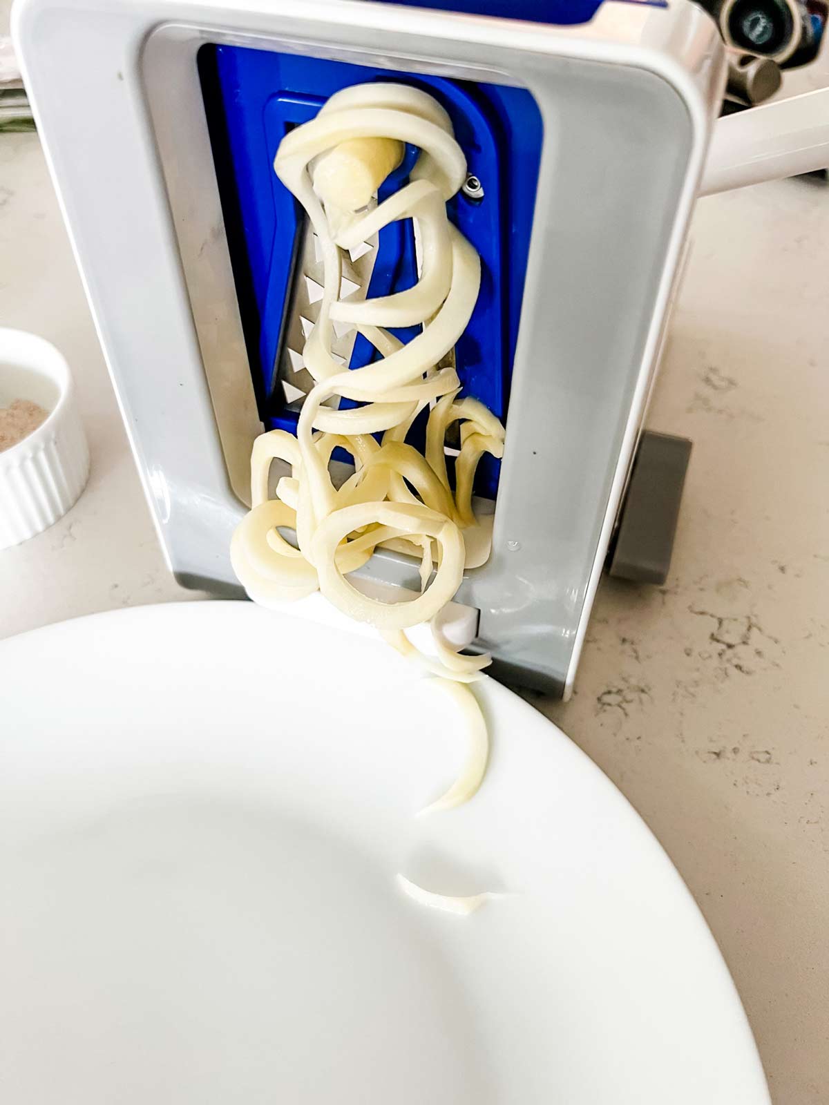 French fries being cut with a spiralizer.