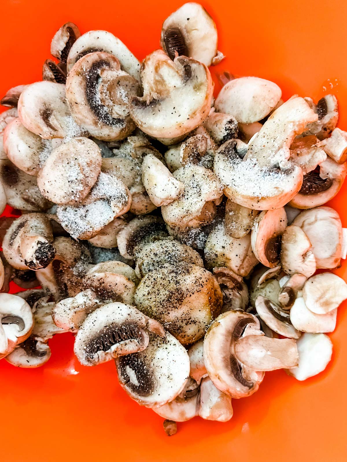 Seasoned mushrooms in an orange bowl.