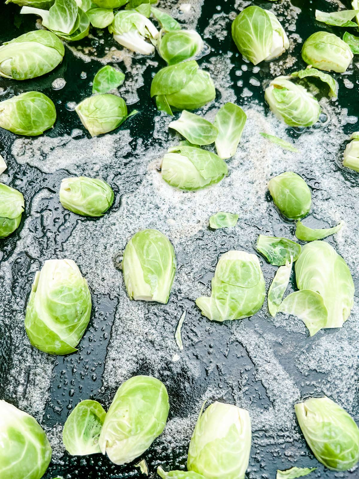 Raw Brussels sprouts that have just been added to a Blackstone griddle.