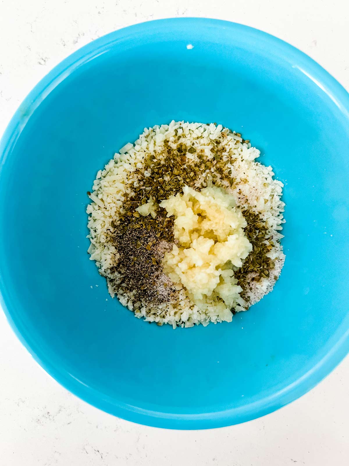 Parmesan, garlic, and seasonings in a small blue bowl.