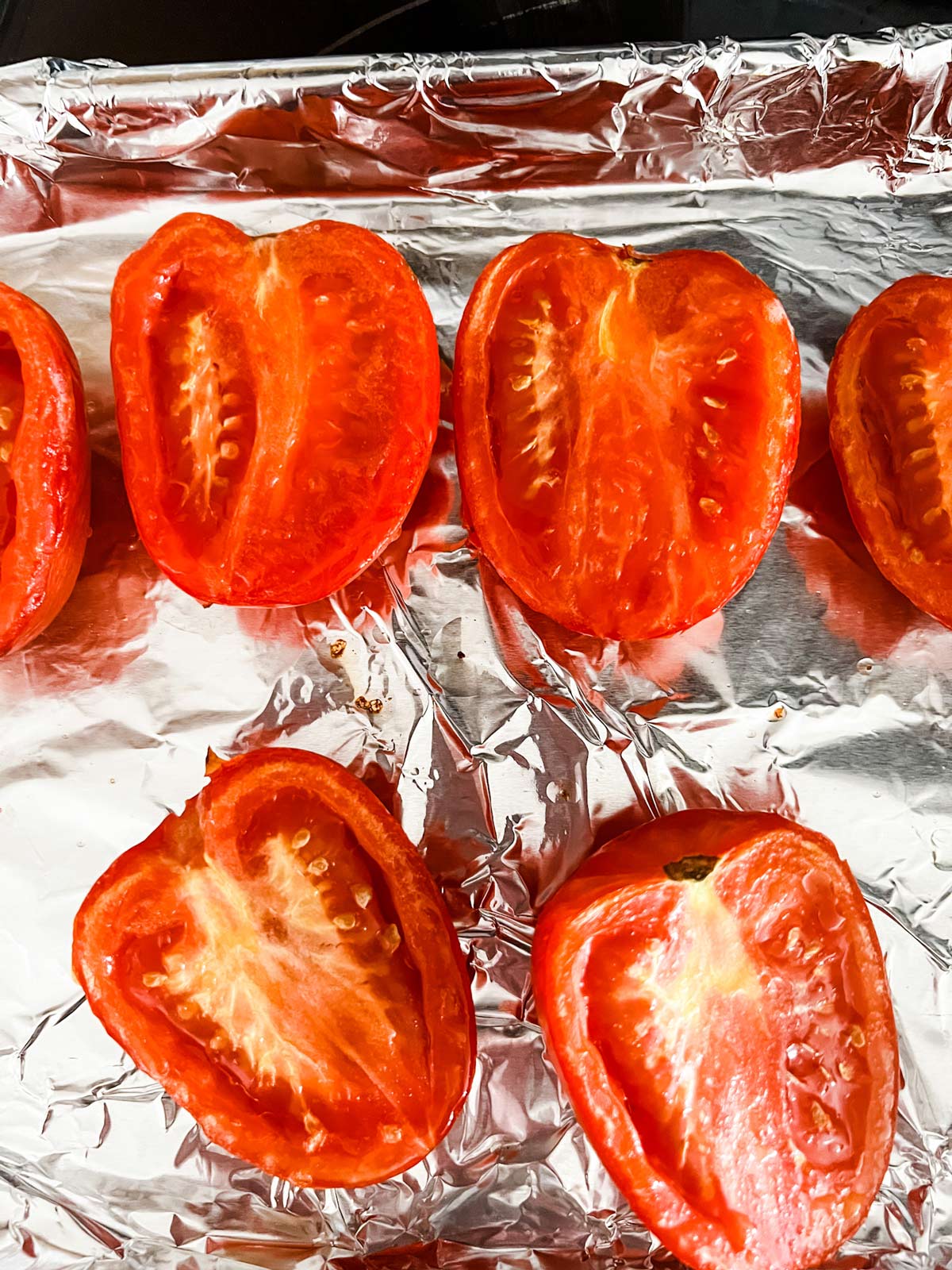 Boiled tomatoes on a foil lined sheet pan.