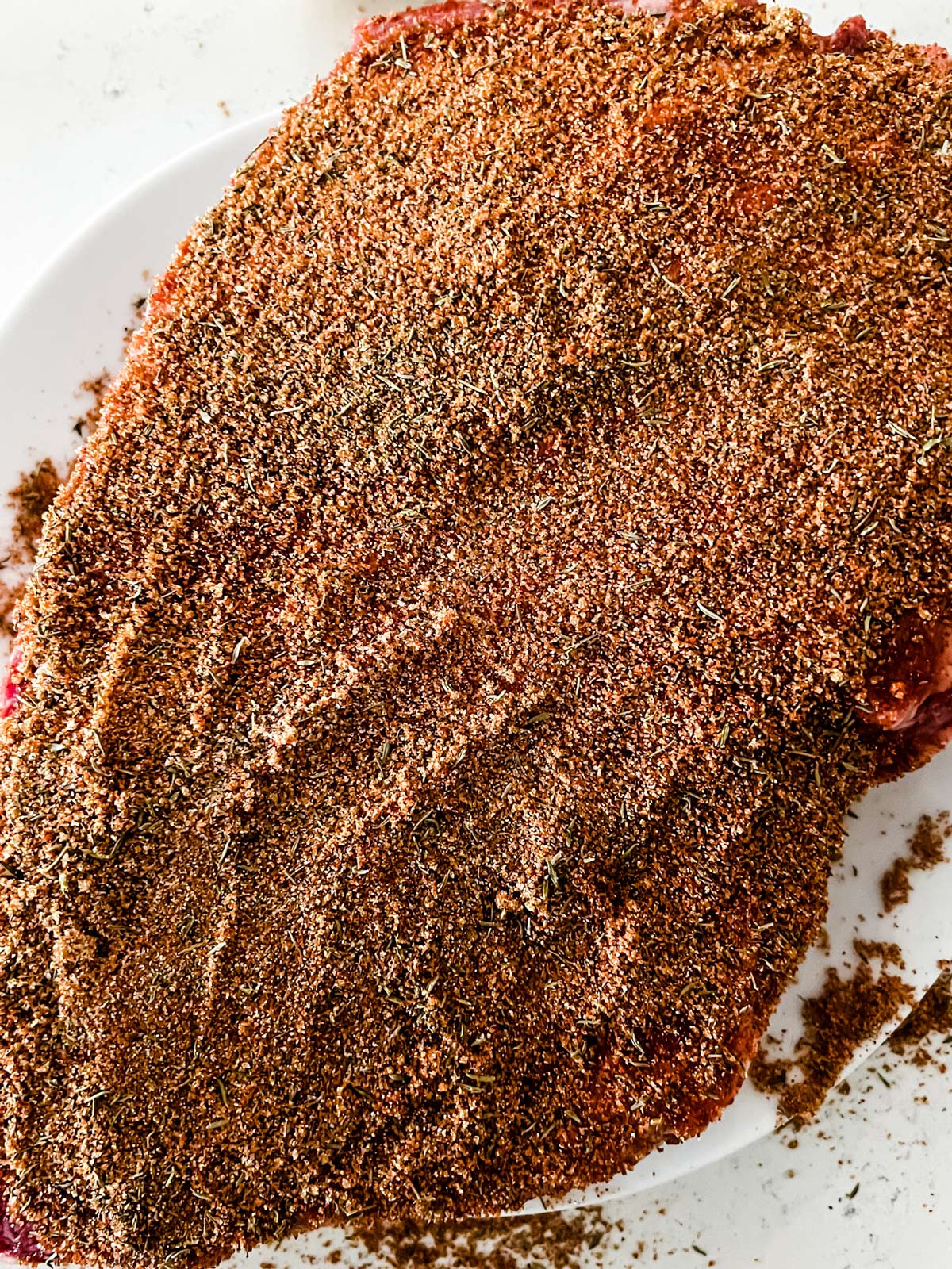 A raw brisket covered in a dry rub.