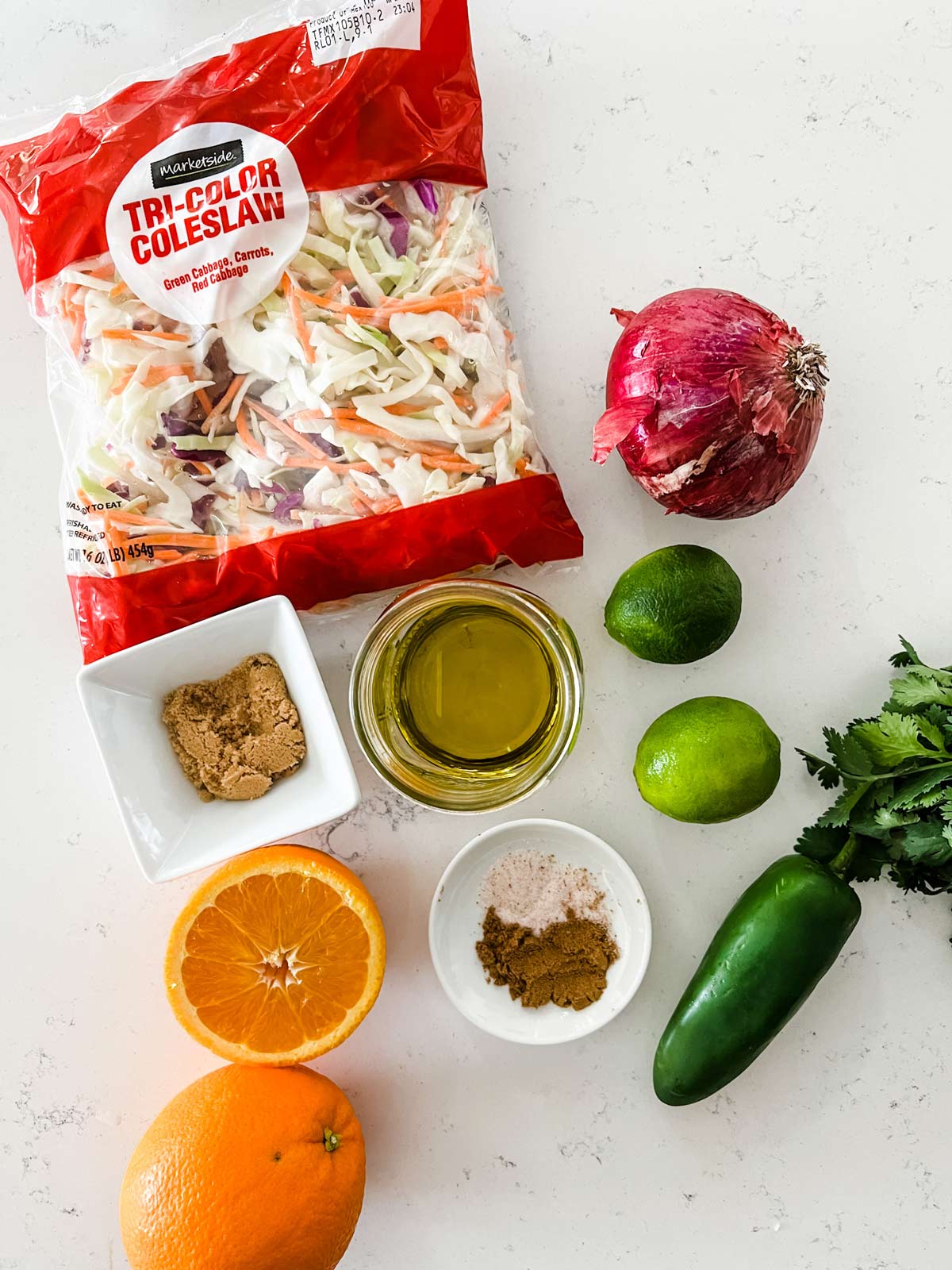 Overhead photo of slaw mix, onion, jalapeno, orange juice, lime juice, oil, and seasonings.