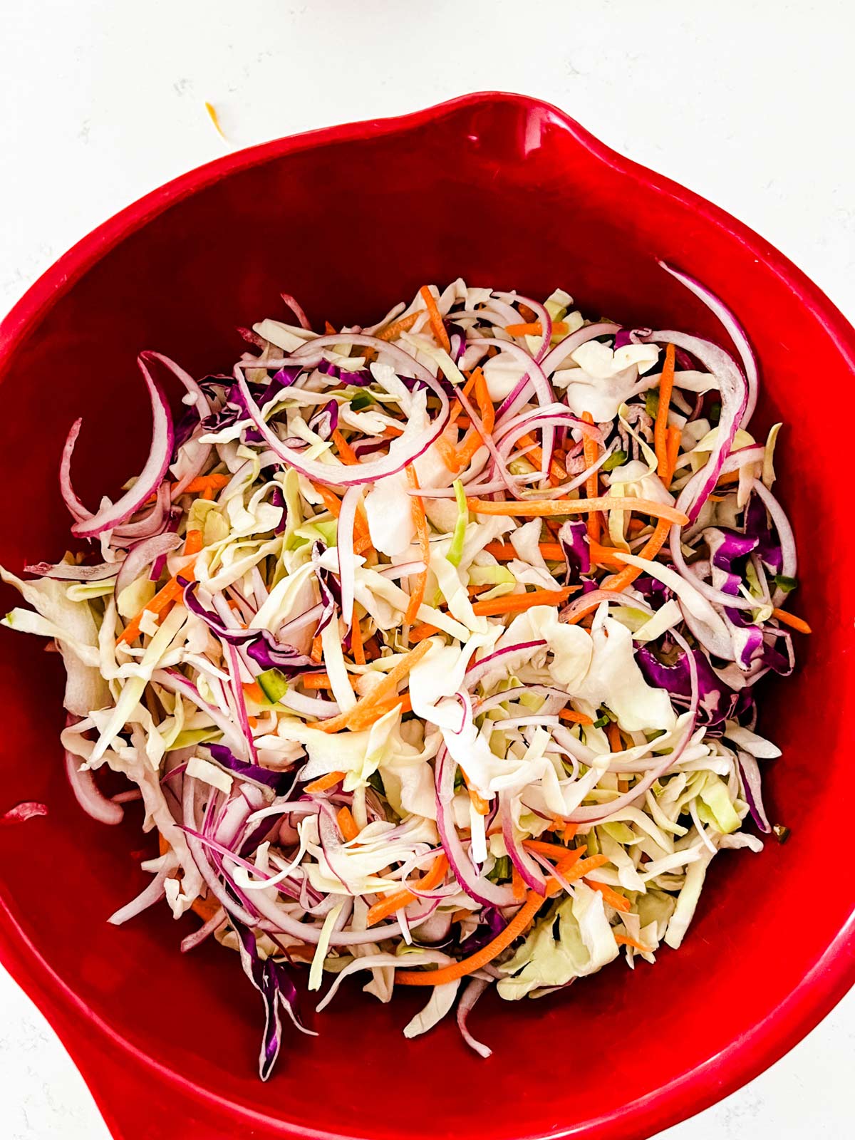 Tossed mexican slaw in a red bowl.