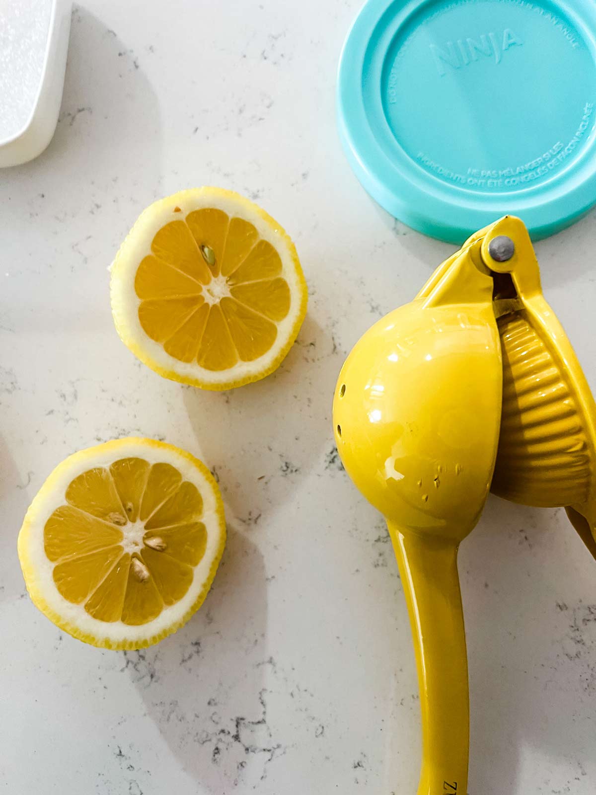 A halved lemon sitting next to a lemon juicer.
