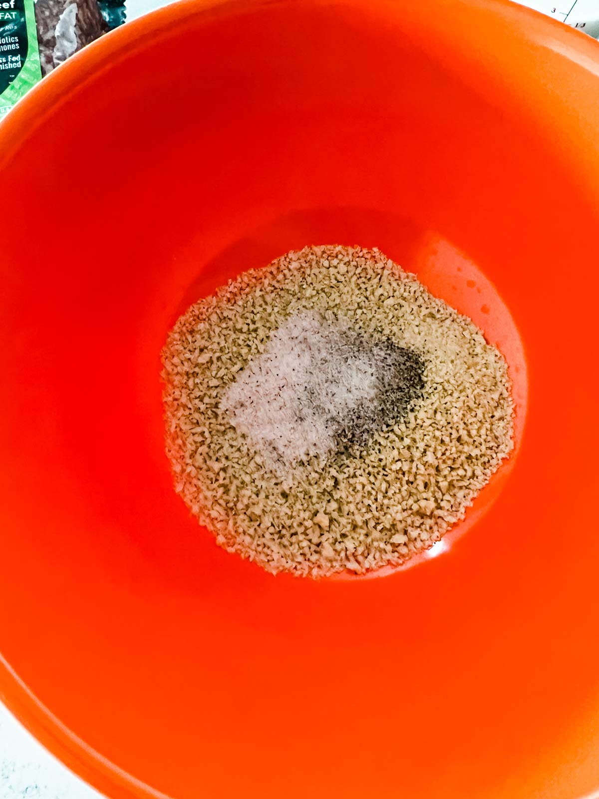 Overhead photo of breadcrumbs and seasonings in an orange bowl.