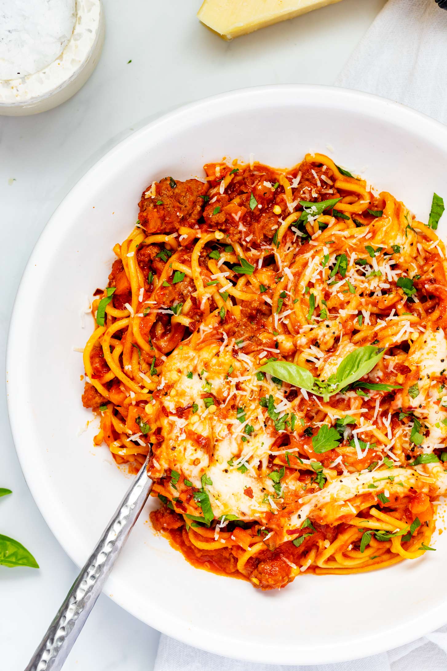 Overhead photo of Ninja Foodi spaghetti on a white plate garnished with basil.