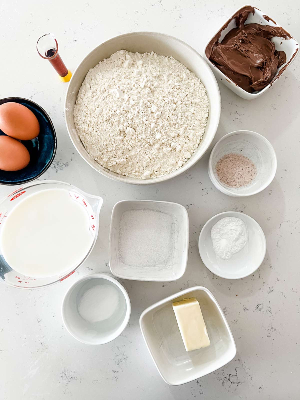 Overhead photo of flour, sugar, baking soda, baking powder, salt, eggs, milk, butter, and Nutella.