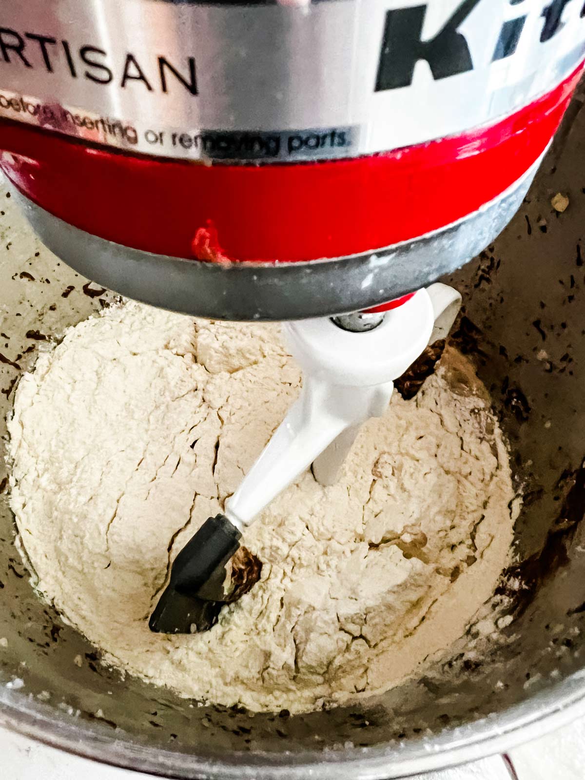 Dry ingredients being added to Eggs, milk, butter, Nutella, and vanilla in the bowl of a stand mixer.