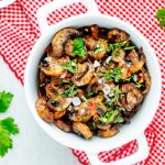 Overhead square photo of air fryer mushrooms garnished with parsley.