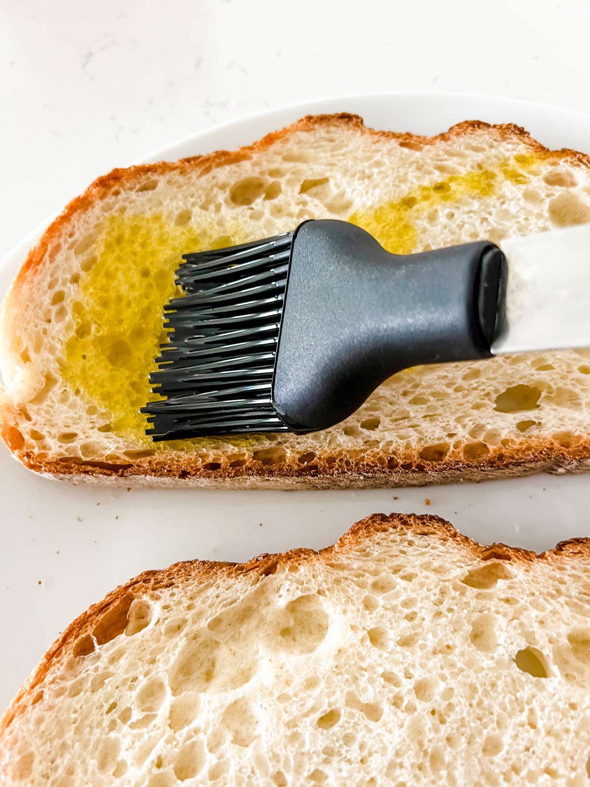 Bread being brushed with olive oil.