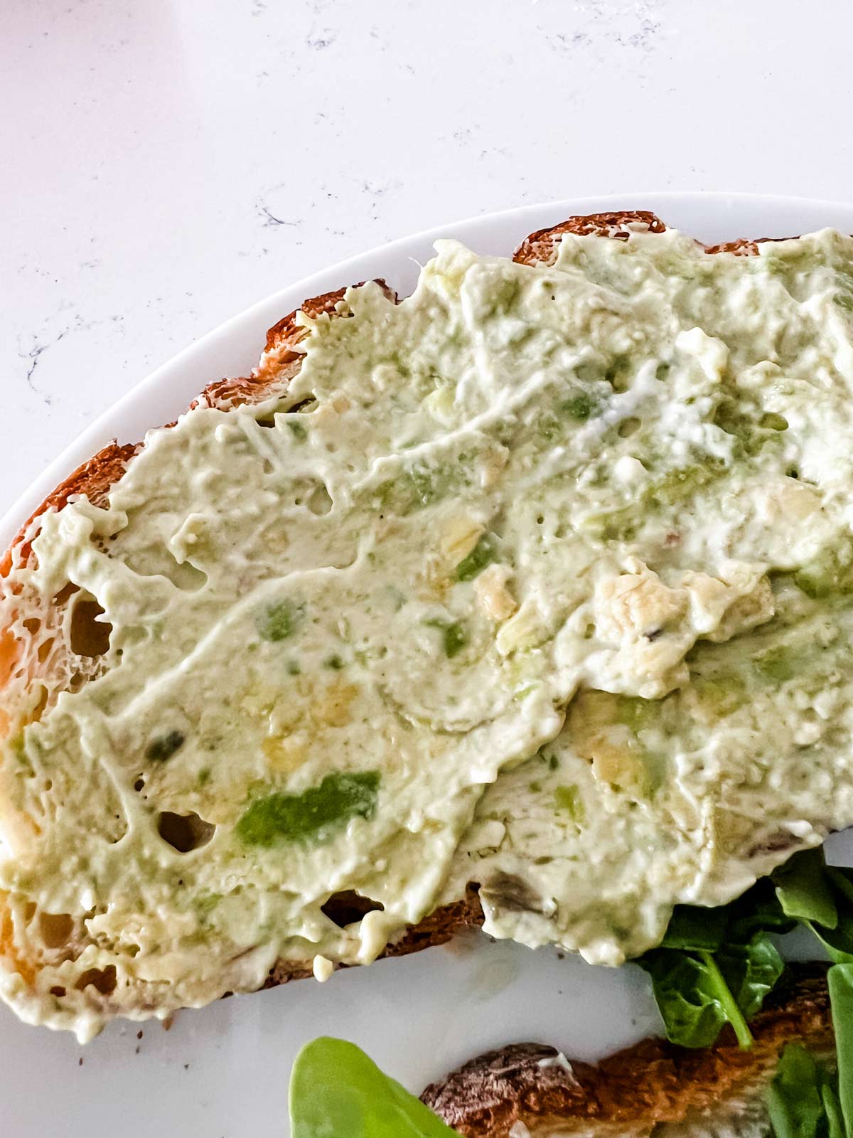 An avocado mayo mixture spread on a slice of bread.