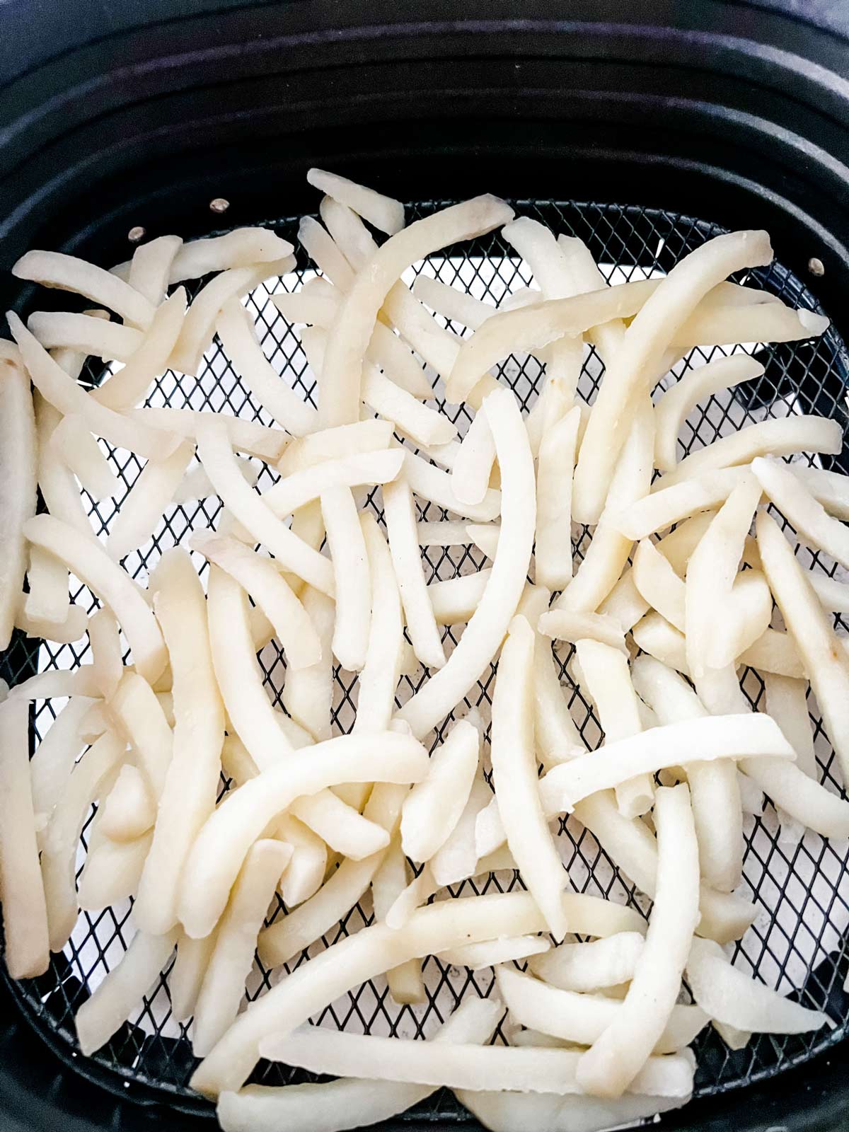 Photo of french fries cooking in an air fryer.