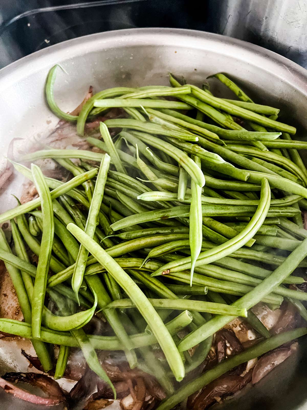 Green beans being added to a skillet.
