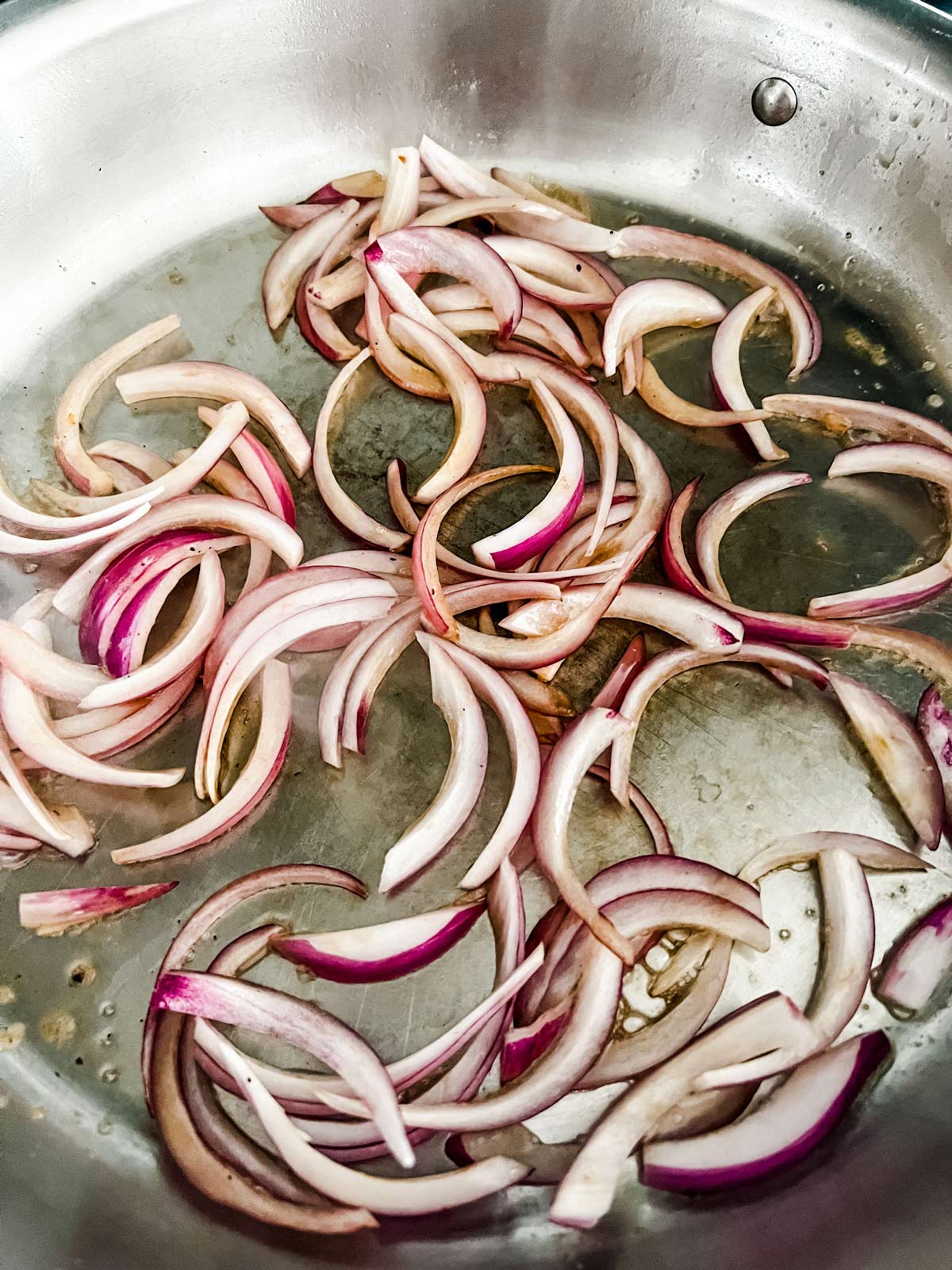 Photo of red onion cooking in a skillet.