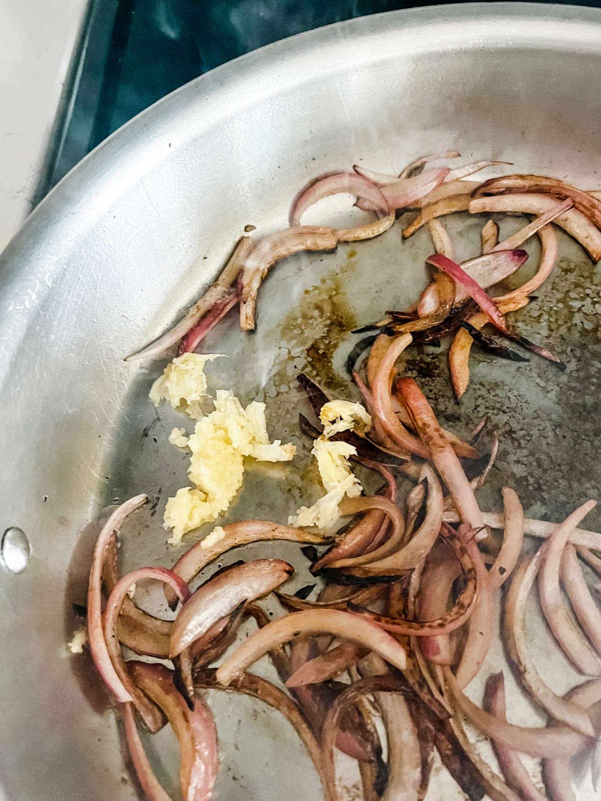 Photo of garlic and red onion cooking in a skillet.