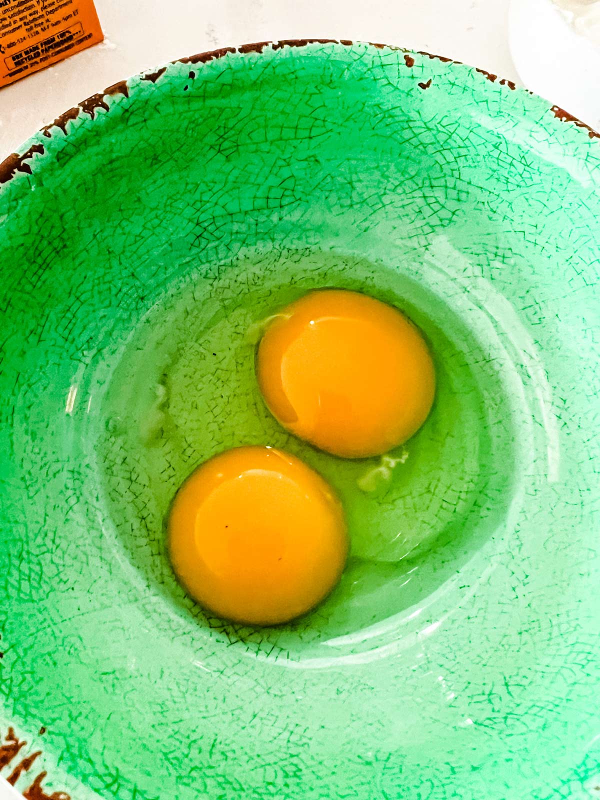 An egg yolk and egg in a bowl.