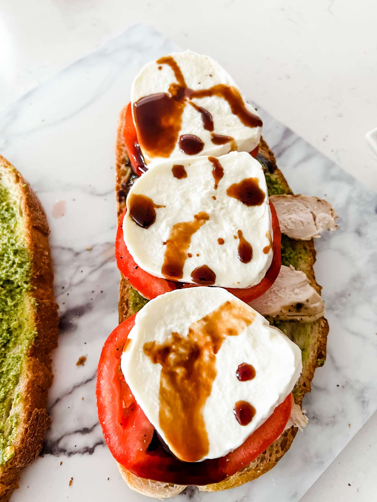 Reduced balsamic vinegar on top of fresh mozzarella on a piece of bread.