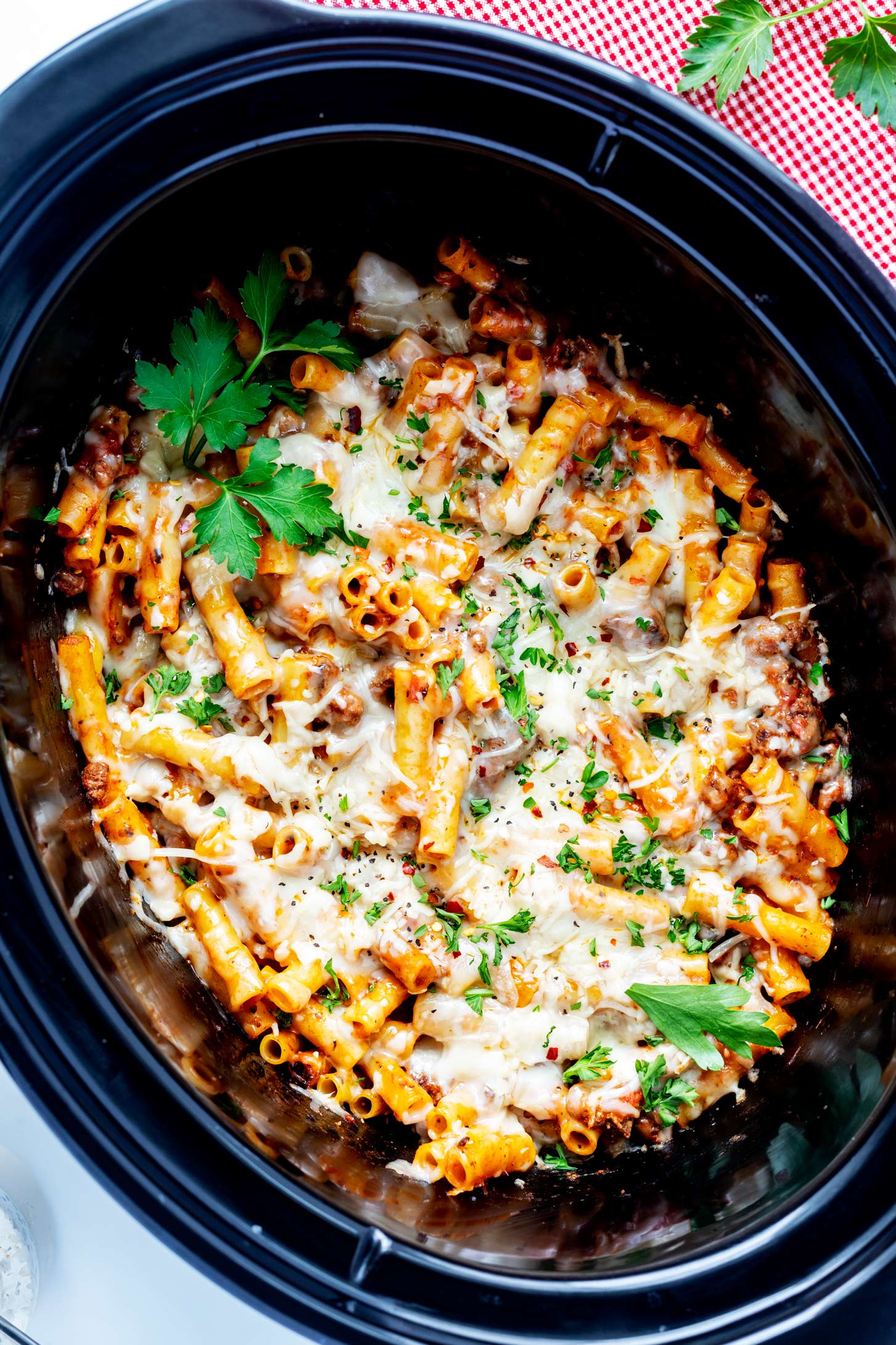 Overhead photo of baked ziti in a crockpot garnished with parsley.